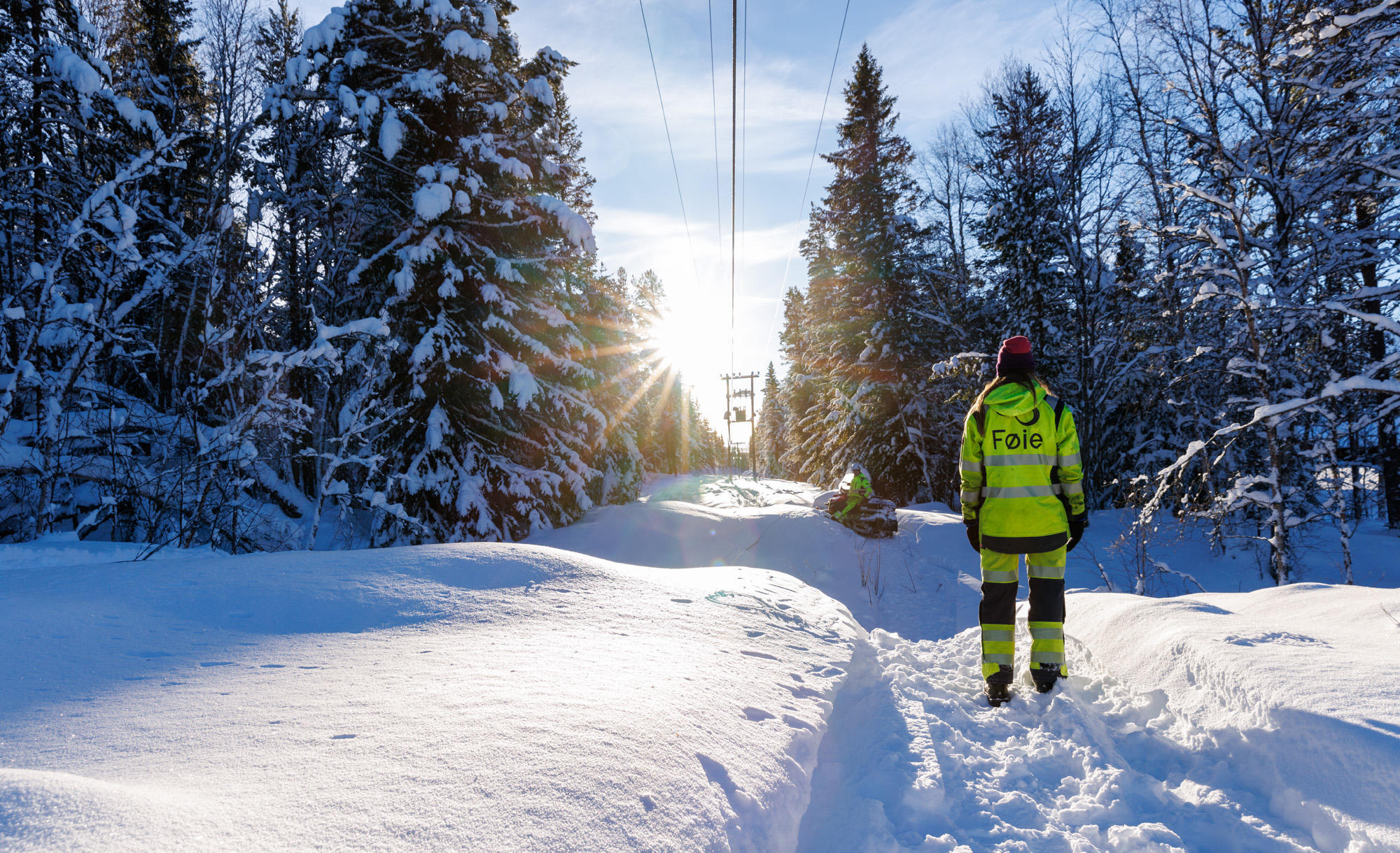 Montør går i snøen under strømlinjer. Foto: Ringerikskraft / Heidi Fauske